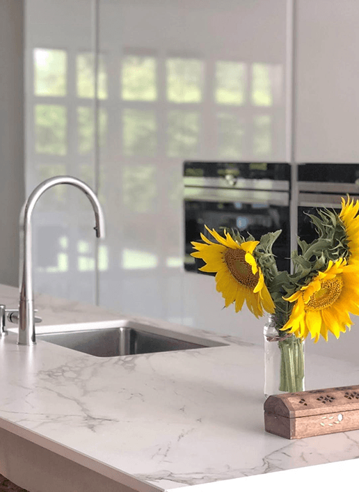 White marble quartz kitchen countertop with undermount sink and sunflowers in Denver home