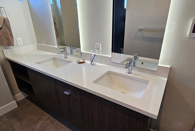Floating dark wood double vanity with a white stone countertop, two undermount sinks and tall backlit mirrors