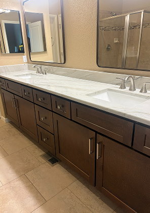 Dark wood double vanity with a white veined stone countertop, two undermount sinks, chrome faucets and black-framed mirrors