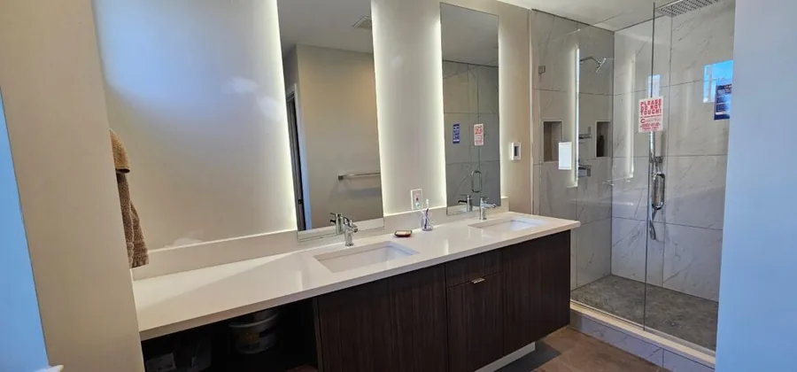 Bathroom vanity beside a glass-enclosed walk-in shower with tile flooring