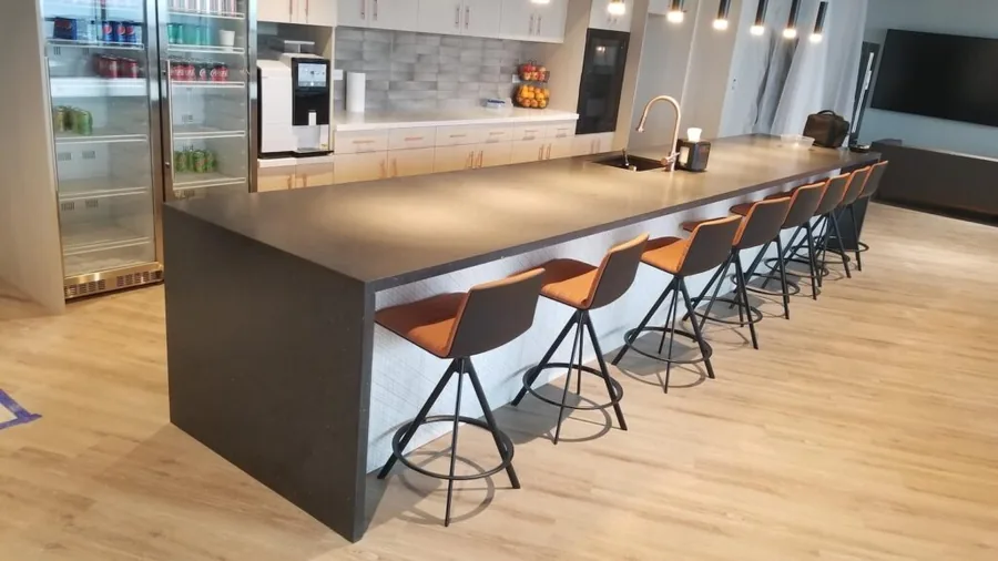 Long dark bar counter with orange stools in a Denver office break room