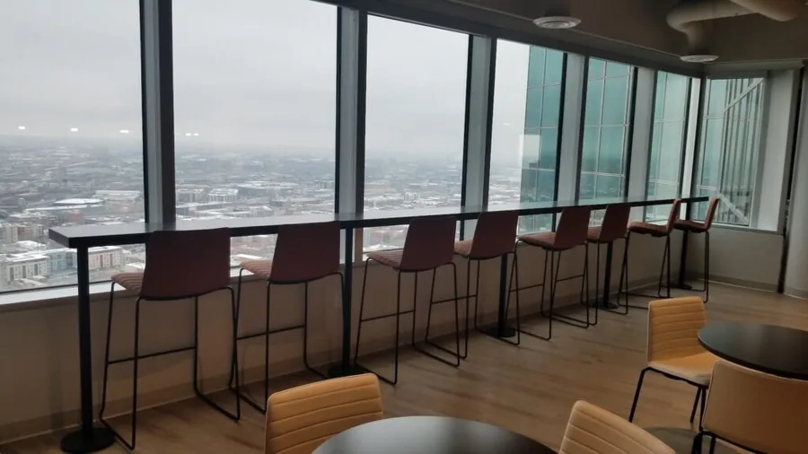 Bar-height counter and stools beside floor-to-ceiling windows in an office lounge