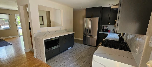 Dark shaker kitchen cabinets with a quartz waterfall countertop, built-in microwave, and stainless steel French door refrigerator