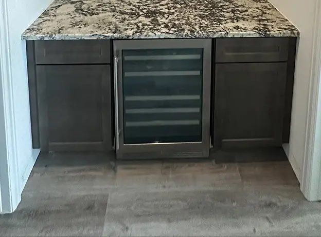 Beverage bar with a heavily veined granite countertop, dark shaker cabinets, and a built-in stainless steel wine refrigerator