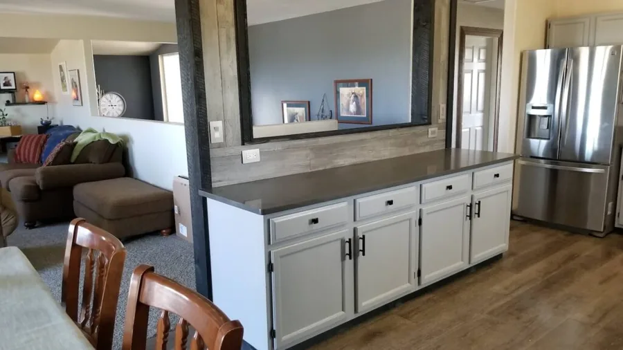 Gray cabinet kitchen with dark countertops opening to the living room through a wide pass-through
