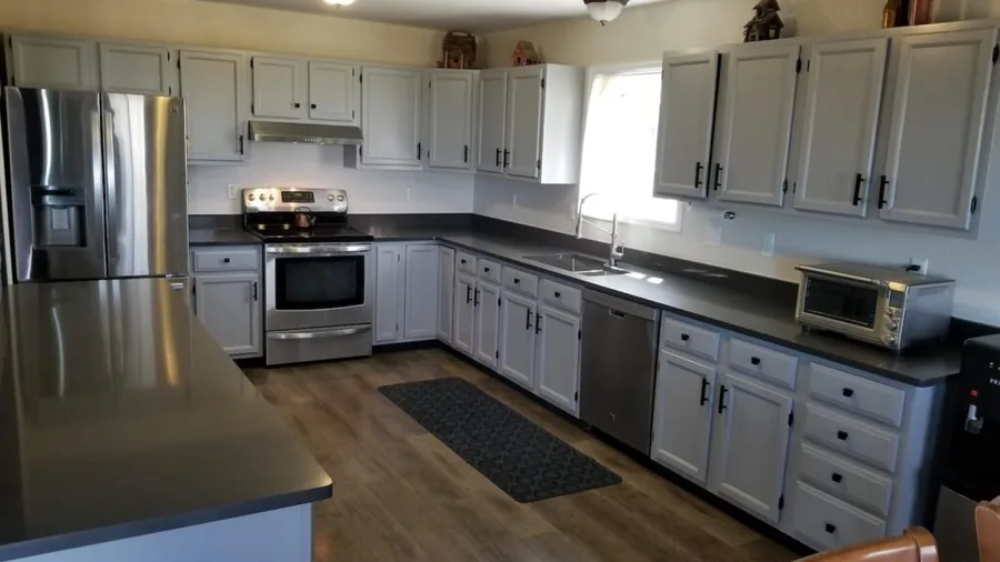 Gray shaker cabinets and dark countertops along a galley kitchen with stainless appliances
