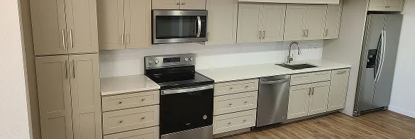 Greige shaker kitchen cabinets with white quartz countertops and stainless steel appliances