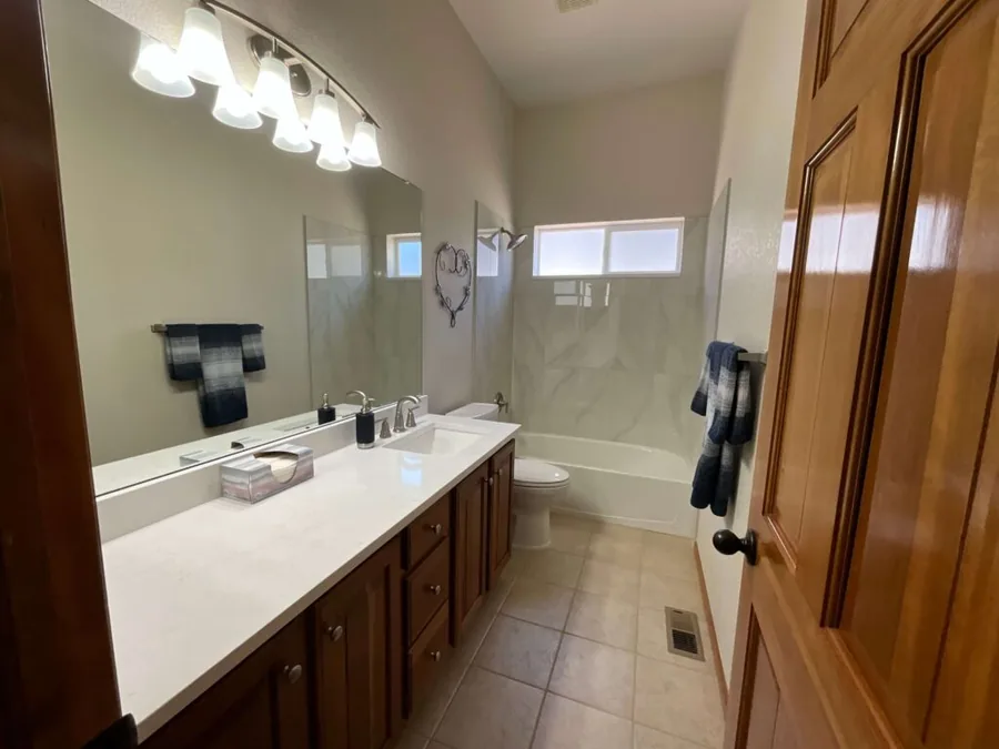Remodeled hall bathroom with a new vanity, framed mirror and tub surround