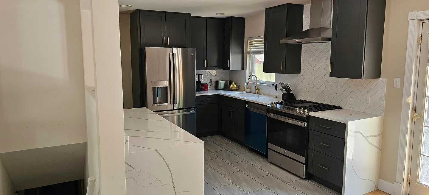Kitchen with dark painted cabinetry and a stainless steel refrigerator