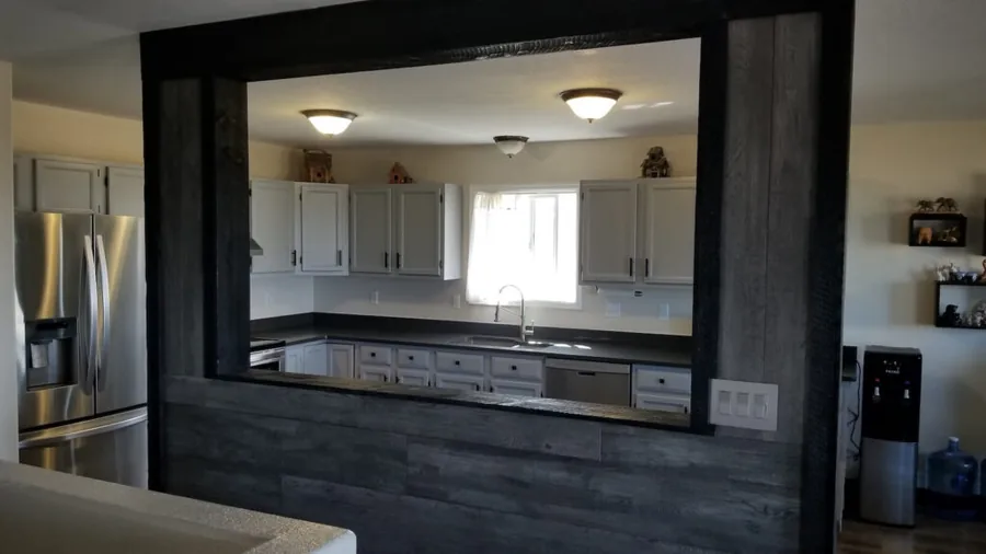 Dark wood framed pass-through opening between a remodeled kitchen and the adjoining room