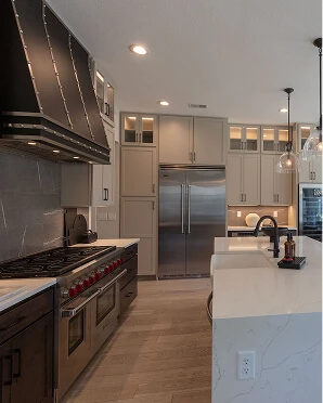 Luxury kitchen with professional dual gas range, custom black hood, quartz waterfall island, and built-in stainless refrigerator