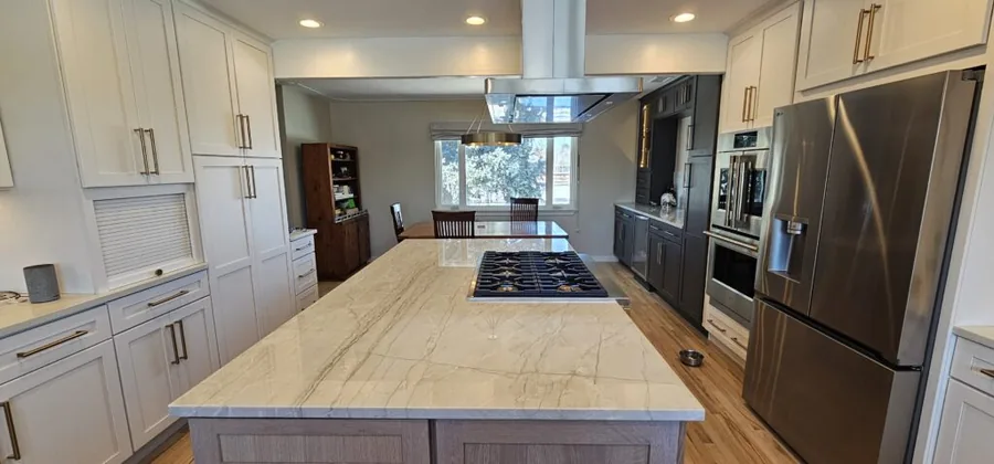 Marble-look island with a cooktop in a white and gray kitchen remodel