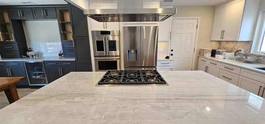 Navy and white kitchen with a quartz island, gas cooktop and stainless hood