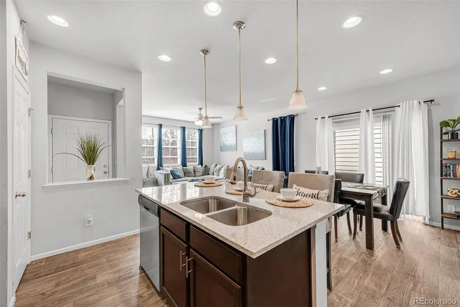 Open concept kitchen island with a sink and pendant lights beside the dining area