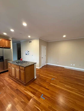 Open-concept kitchen with oak island, gas cooktop, stainless refrigerator, and hardwood floors before remodeling