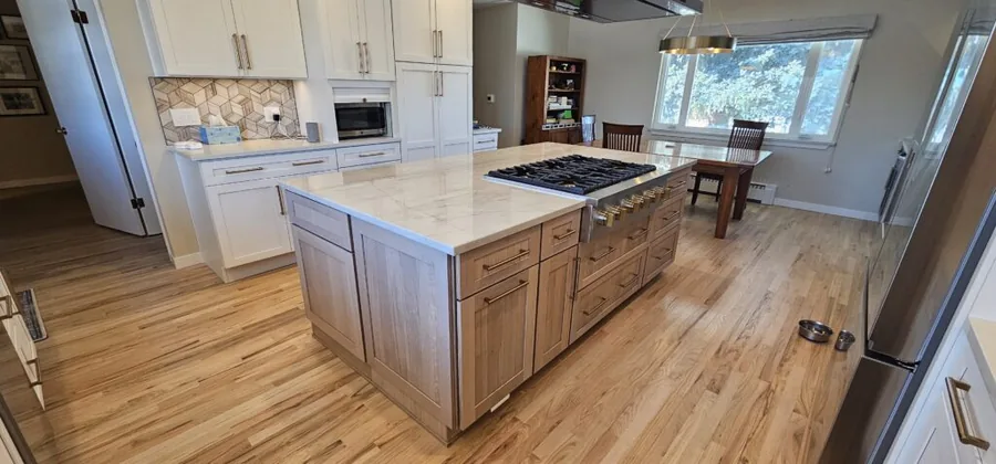 White perimeter cabinets with a stained wood island and gas range