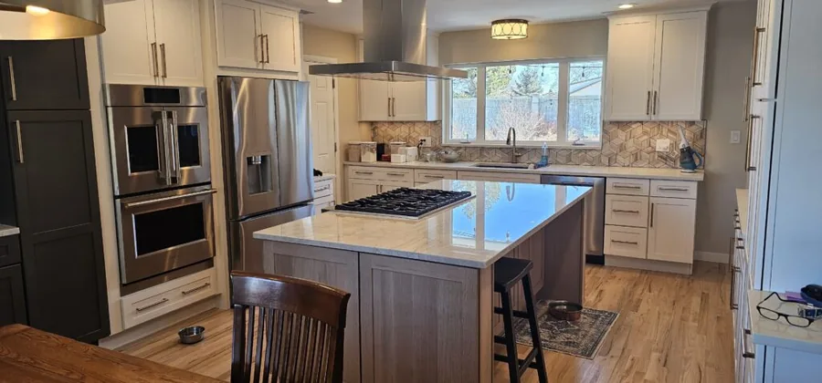 White shaker cabinets, a wood island and an island range hood in a remodeled kitchen