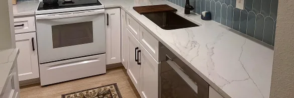 White shaker cabinets with marble-look quartz countertops and blue fish scale tile backsplash